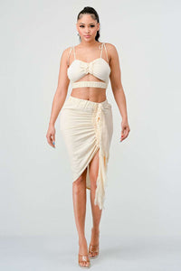 Cream Dream Ruched Set: Soft cream crop top with adjustable spaghetti ties and charming bow detail, paired with a high-waisted midi skirt featuring flattering ruching and playful fringe tassels.