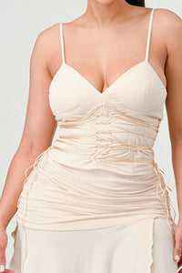 Stylish cream dress with ruched details, thin straps, and high slit