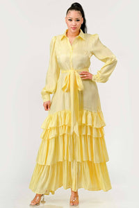 Yellow Tiered Ruffle Maxi Dress with Belt: A bright yellow dress featuring a button-up front, tiered ruffle skirt, and a matching fabric belt at the waist. The dress has long, puffed sleeves and a collared neckline.