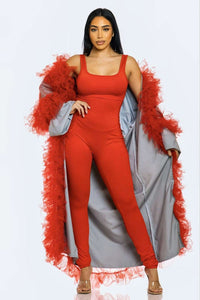 Elegantly posed model in a red jumpsuit that is accentuated with detachable azure sleeves and fiery red feather embellishments.